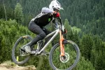 Mountainbiker springt auf einem Trail mit Bäumen im Hintergrund