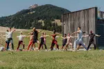 Gruppe von Menschen beim Yoga im Freien, Berge im Hintergrund
