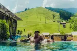 Paar entspannt im Pool vor einer Berglandschaft.