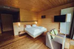 Gemütliches Holzschlafzimmer mit Doppelbett und Fernseher