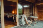 gemütlicher Holzbalkon mit Tisch und Stühlen, Licht von drinnen