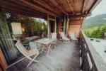 Holzterrasse mit Stühlen und Tischen, umgeben von Grün