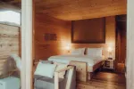 holziges Interieur eines gemütlichen Hotelzimmers mit Bett und Lampen