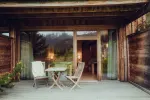 Holzterrasse mit zwei Stühlen und einem kleinen Tisch, umgeben von Pflanzen
