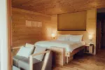 gemütliches Holzschlafzimmer mit Bett, Sessel und sanfter Beleuchtung