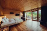 Gemütliches Zimmer mit Holzdecke, Bett und Blick auf die Natur