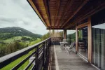 Holzterrasse mit Blick auf grüne Hügel und Wolken am Himmel