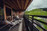 Holzbalkon mit Liegestühlen, Blick auf grüne Hügel