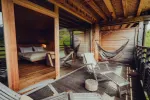 Holzterrasse mit Hängematten, Liegestühlen und einem Blick auf ein Schlafzimmer.
