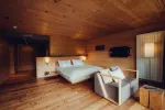 Gemütliches Schlafzimmer mit Bett, Sessel und warmem Holzdécor