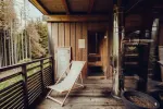 Holzbalkon mit Liegestuhl und Grün im Hintergrund