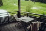 Holzbalkon mit Tisch und Stuhl mit Blick auf grüne Felder