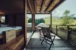 Holzbalkon mit Stühlen mit Blick auf eine grüne Landschaft