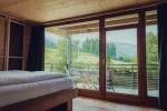 Modernes Schlafzimmer mit großen Fenstern und Blick auf eine grüne Landschaft