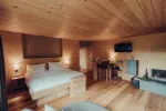 gemütliches Schlafzimmer mit Holzakzenten, Doppelbett, Fernseher und Sitzecke