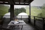 Blick von einer Holzveranda auf grüne Hügel und weiße Kuppeln