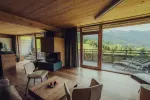Modernes Wohnzimmer mit Holzboden und großen Fenstern mit Blick auf die Berge