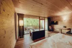 Innenansicht eines Holzraums mit Bett und Sitzecke