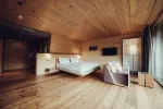 stilvolles Schlafzimmer mit Holzboden, Bett, Sofa und Stehlampe