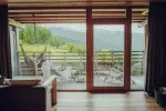 Moderner Innenraum mit großen Fenstern, die auf Berge und eine Terrasse blicken
