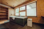 modernes Badezimmer mit Badewanne, Fenster und Holzregalen