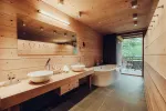 modernes Badezimmer mit Holzwänden, Doppelwaschbecken und freistehender Badewanne