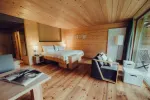 Innenansicht eines gemütlichen Holzhotelzimmers mit Bett und Sitzbereich