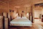 Helles Schlafzimmer mit einem Bett aus Holz und Holzsäulen.