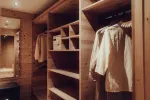 Holzkleiderschrank mit hängender Kleidung und Regalen