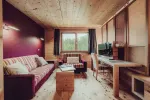gemütlicher Wohnraum mit Sofa, Holzmöbeln und Schreibtisch am Fenster