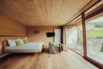 modernes Schlafzimmer mit Holzwänden und großen Fenstern