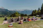 Gruppe von Menschen sitzt im Freien mit Bergpanorama
