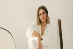 Frau im weißen Outfit, die neben einem runden Spiegel sitzt