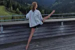 Person tanzt auf einem Holzdeck mit malerischen Bergen im Hintergrund