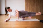 Person, die einen Seitstütz auf einer Yogamatte drinnen ausführt
