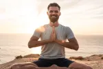 Mann im Meditationspose am Ozean bei Sonnenuntergang