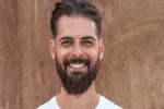 Lächelnder Mann mit Bart vor einem Holzhintergrund