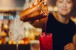 Barkeeper, der einen roten Cocktail in ein Glas gießt