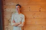 Person lächelt vor einer Holzwand
