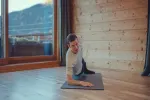 Person macht Yoga auf einer Matte in einem Holzraum