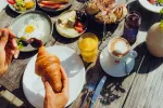 Tischgedeck mit Croissant, Eiern, Gemüse und Getränken.