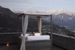 Person entspannt auf einem Bett mit Bergblick bei Sonnenuntergang
