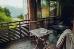Blick von einem Balkon mit Tisch und Stühlen, mit Aussicht auf Grün und Berge