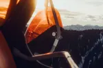Nahaufnahme eines Skilifts mit orangefarbenen Sitzen und Schneelandschaft