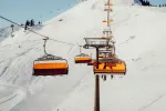 Gelbe Gondeln in einer Bergbahn über verschneitem Gelände