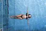 Person schwimmt unter Wasser in einem blauen Pool