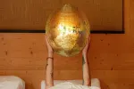 Person hält einen goldenen Globus über einem Bett