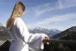 Person in einem Bademantel mit Blick auf eine Berglandschaft