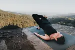 Person macht Yoga auf einem Bergvorsprung