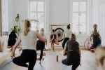 Gruppe von Menschen, die in einem hellen Studio Yoga praktiziert